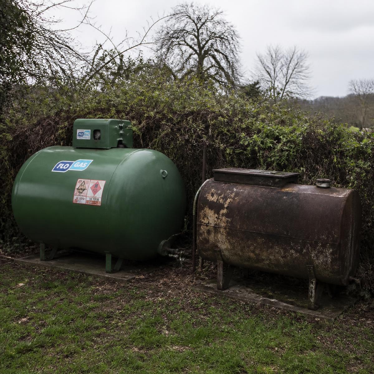 An old oil tank and LPG tank in a rural garden